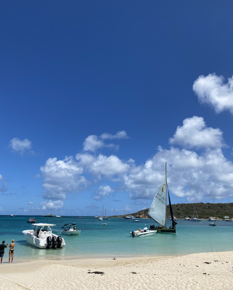 Sandy Ground beach sparkles in the sun and two boats float in the crystal blue water.