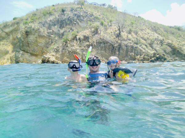 A parent and two children snorkel off the shores of Anguilla in the Caribbean while on vacation